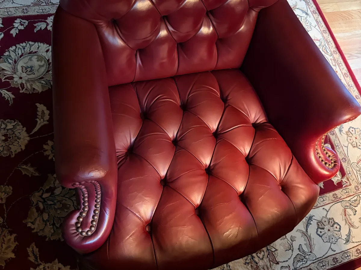 Vintage oxblood Chesterfield armchair after restoration — armrests rebuilt, cracks repaired, color restored by Leather & Vinyl Care NYC